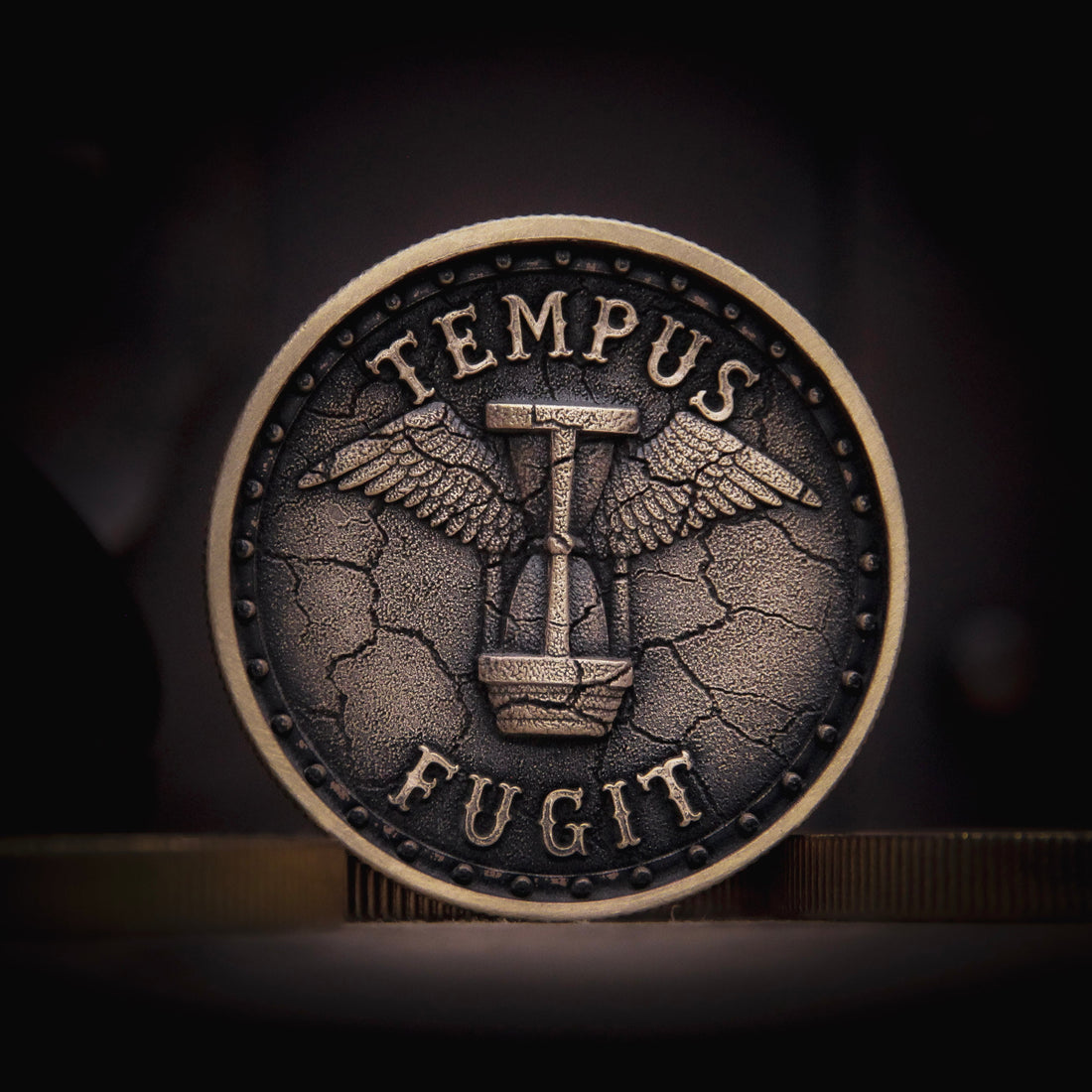 Antique-style brass EDC coin featuring the Latin phrase “Tempus Fugit” with a winged hourglass at the centre, symbolizing the passage of time.