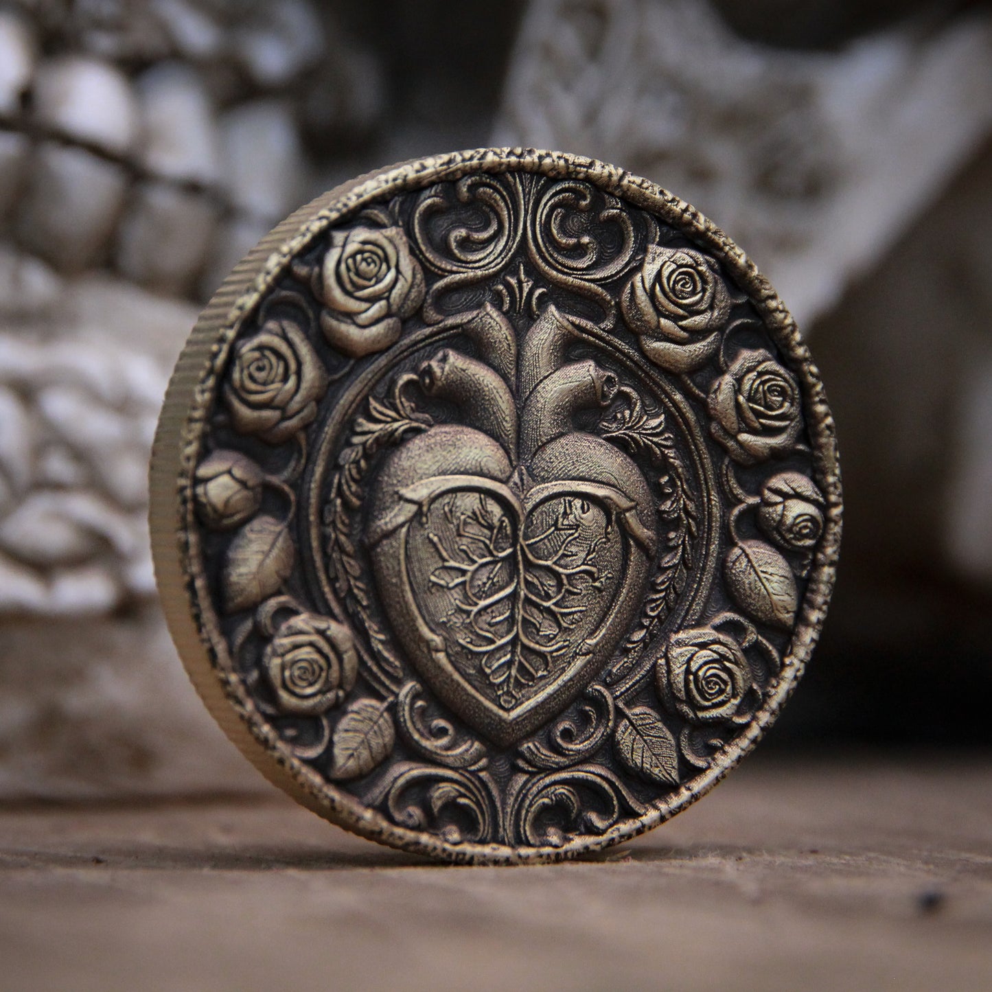 Decorative metal coin with heart and rose design on a textured surface