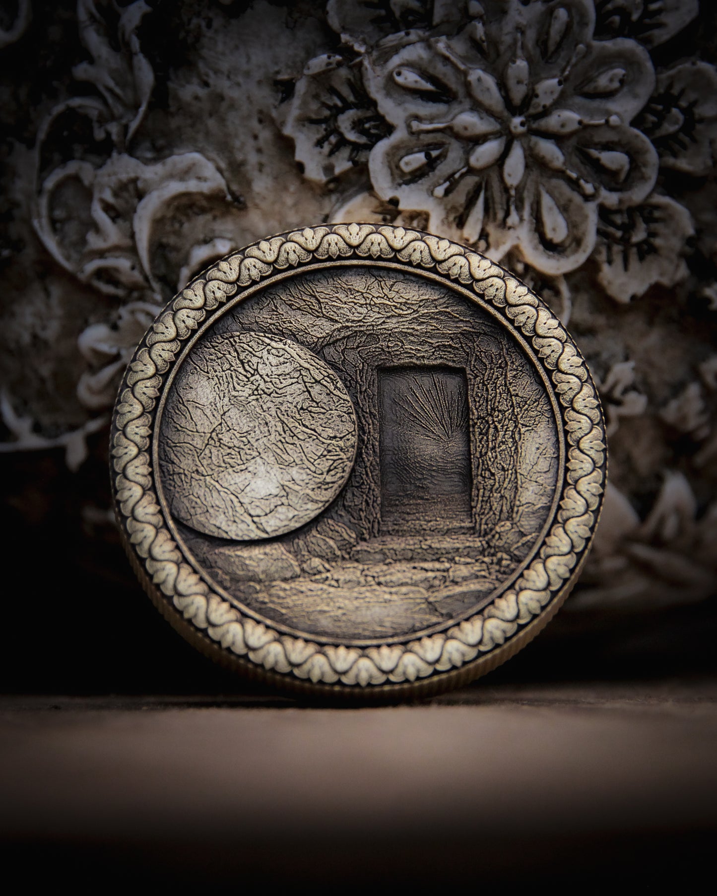 Decorative coin with intricate design of the empty tomb on a textured surface