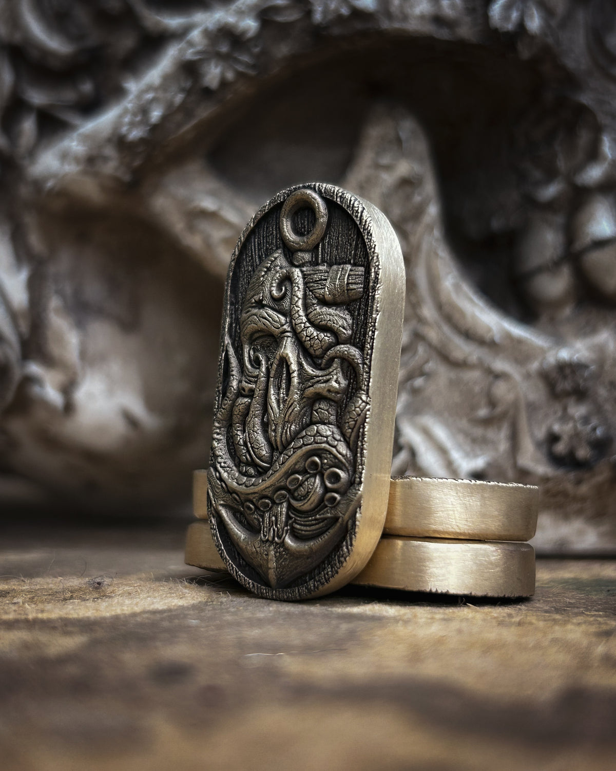 Side view of the kraken fidget pill showing raised tentacles, detailed suckers, recessed engraving and a smooth metal edge.