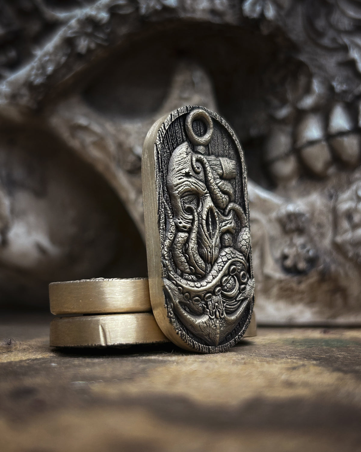 Front view of the kraken and anchor engraving, showing textured tentacles and polished highlights against an antiqued background.