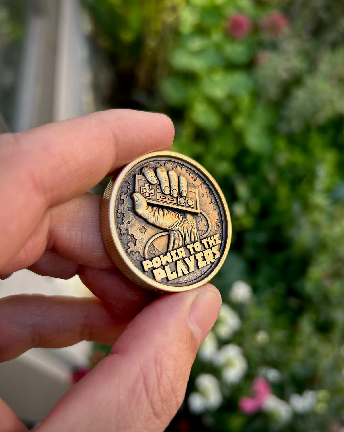 Side angle of the Power to the Players coin, showing its ridged edge and the depth of the controller and hand engraving.