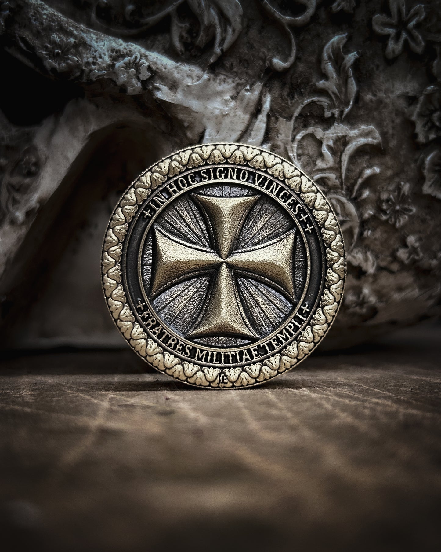 Decorative coin with intricate templar cross design on a textured surface