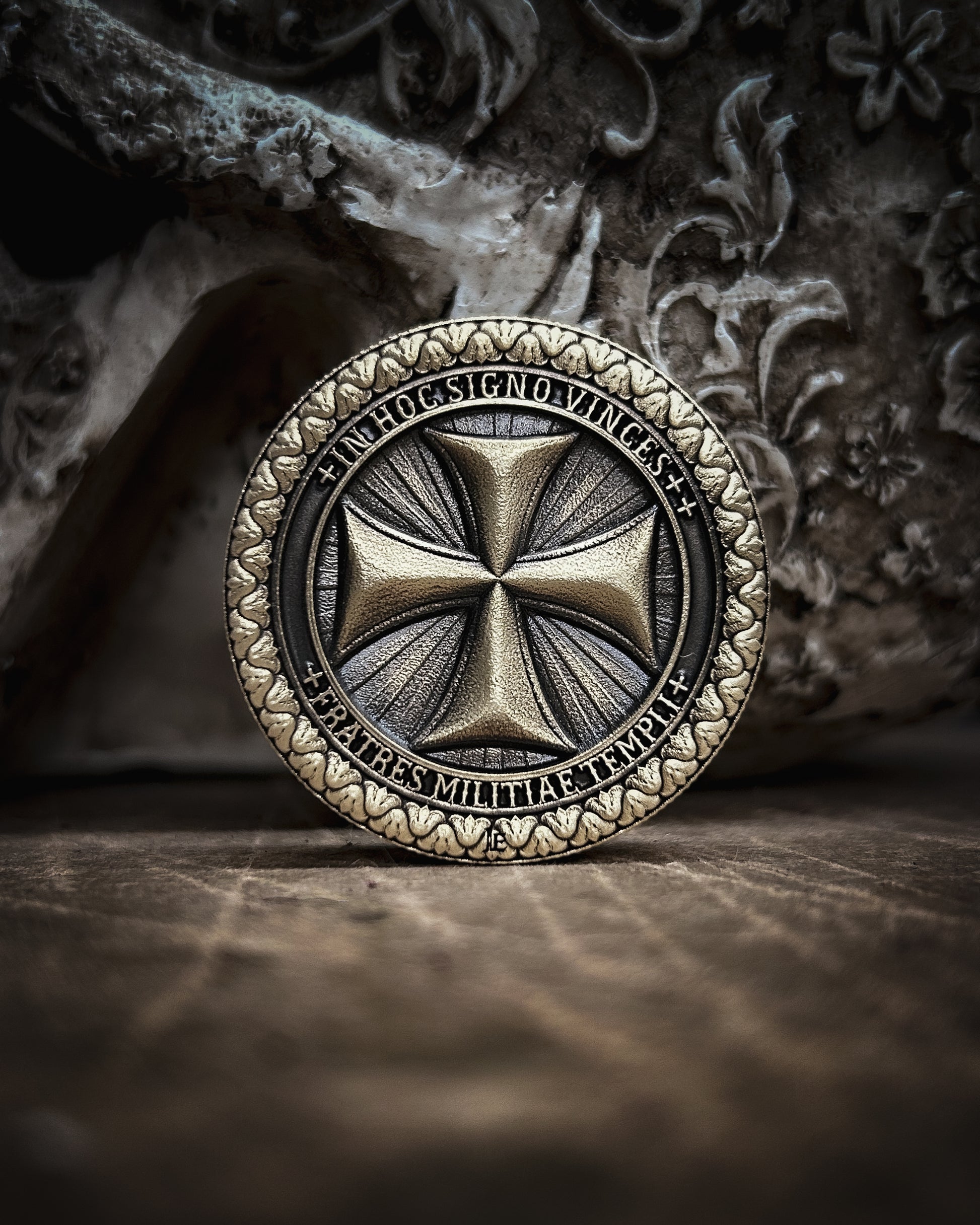 Decorative coin with intricate templar cross design on a textured surface