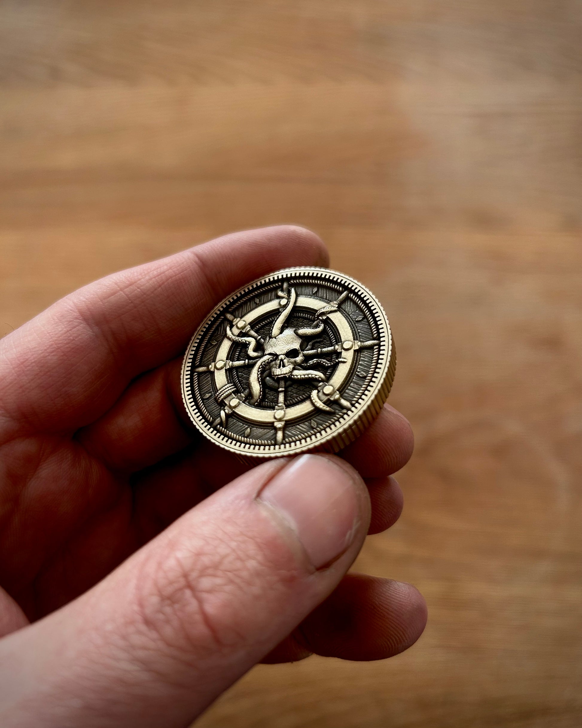 Hand holding a decorative coin with intricate design against a wooden background