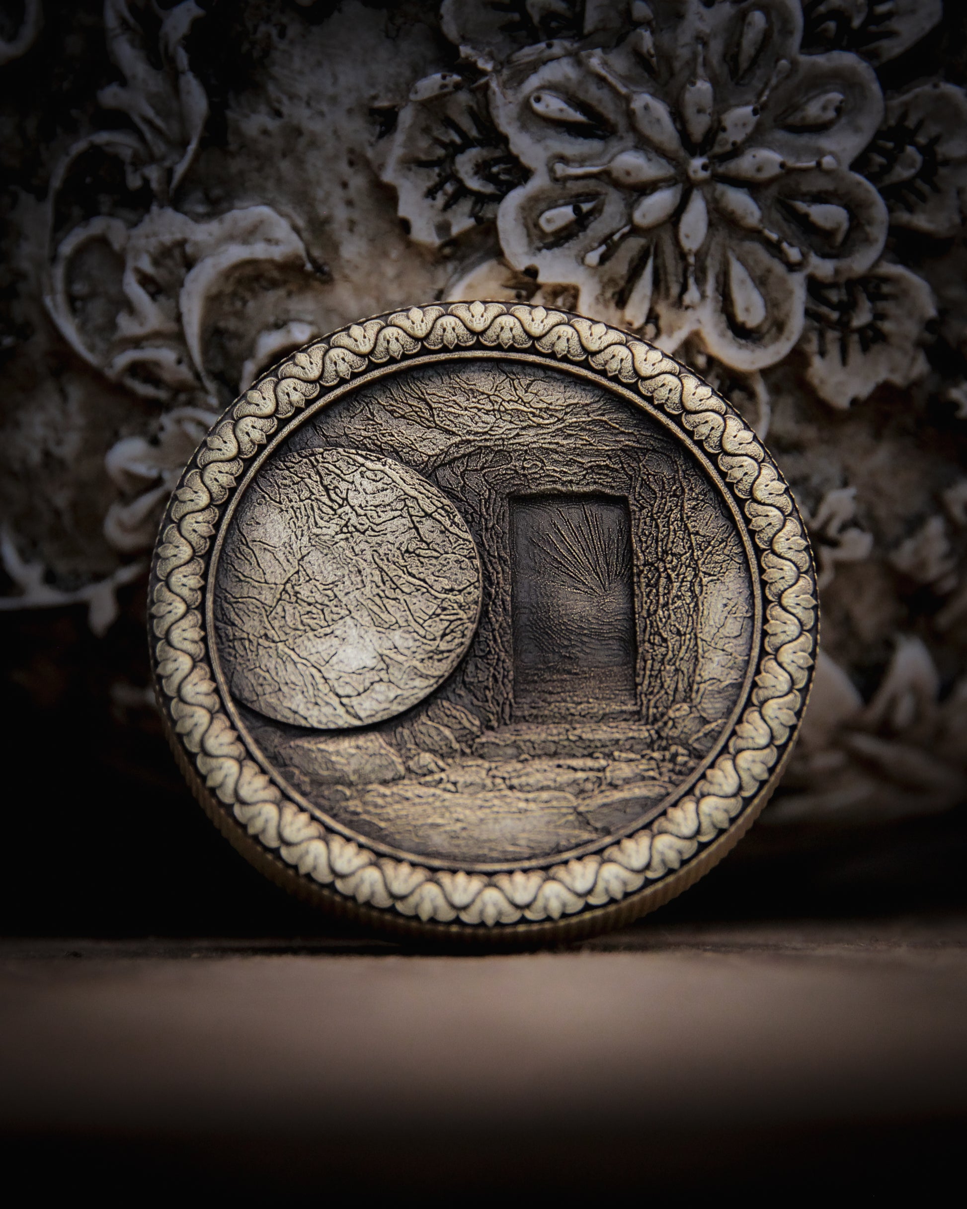 Decorative coin with intricate design of the empty tomb on a textured surface