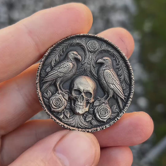 Decorative coin with skull and ravens design on a textured surface