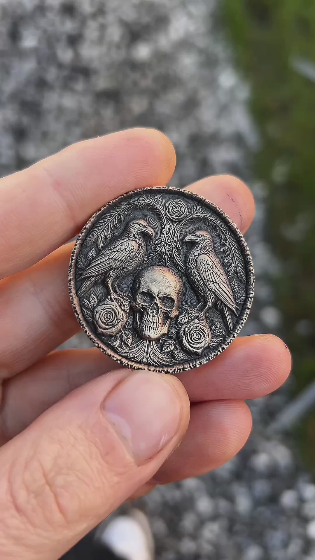 Decorative coin with skull and ravens design on a textured surface