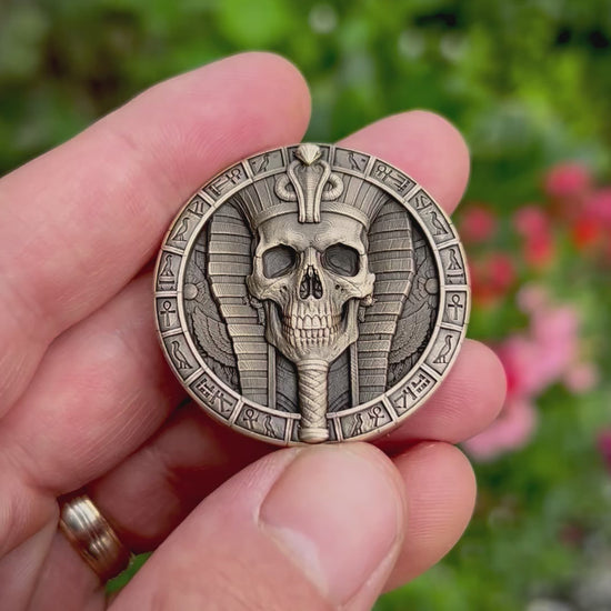 Close-up video of the Pharaoh Skull Coin, tilted to reveal the deep engraving, cobra-topped headdress, decorative Egyptian border and antiqued, hand-finished details.
