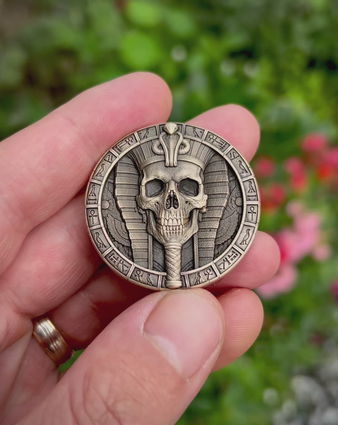 Close-up video of the Pharaoh Skull Coin, tilted to reveal the deep engraving, cobra-topped headdress, decorative Egyptian border and antiqued, hand-finished details.